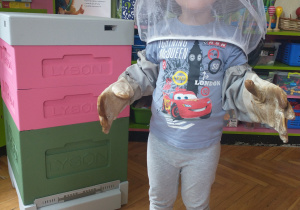 Chłopiec w szarej koszulce w stroju pszczelarza